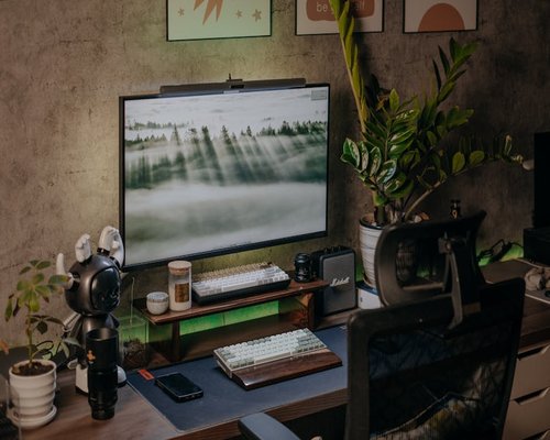 A well organized wooden desk setup with soft ambient lighting and plants