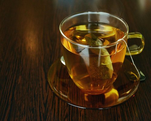 A steaming cup of tea resting on a windowsill looking out at the city